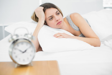 Cute young woman lying exhausted in her bed