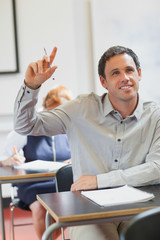 Smiling handsome mature student raising his hand