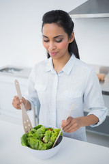 Lovely peaceful woman preparing salad in kitchen