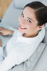 Smiling well dressed young woman using laptop