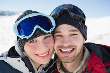 Close-up of a cheerful couple with ski goggles on snow