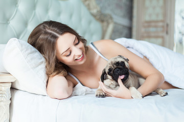 Attractive young girl with dog while laying on bed