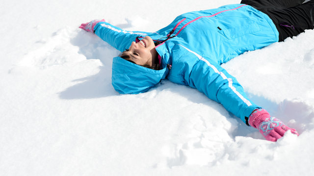 Fun woman liying down in snow - Powered by Adobe
