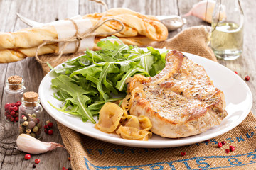 Roasted pork with apples and onions served with fresh arugula