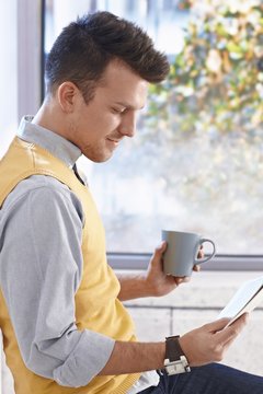 Young man reading news drinking coffee