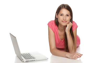 Fototapeta premium Smiling woman with laptop lying on the floor