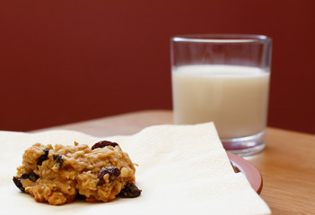 Freshly baked oatmeal raisin cookie with a glass of milk