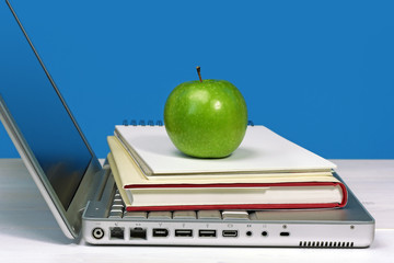 laptop with book, notebook and green apple