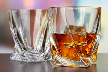 Glasses of whiskey, on bright background