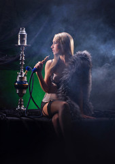 A sexy woman in luxury underwear smoking a hookah