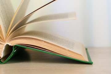Opened book on wooden table on bright background