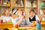 Little redhead schoolboy behind school desk 