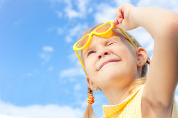 portrait of a happy girl with sunglasses against the sky