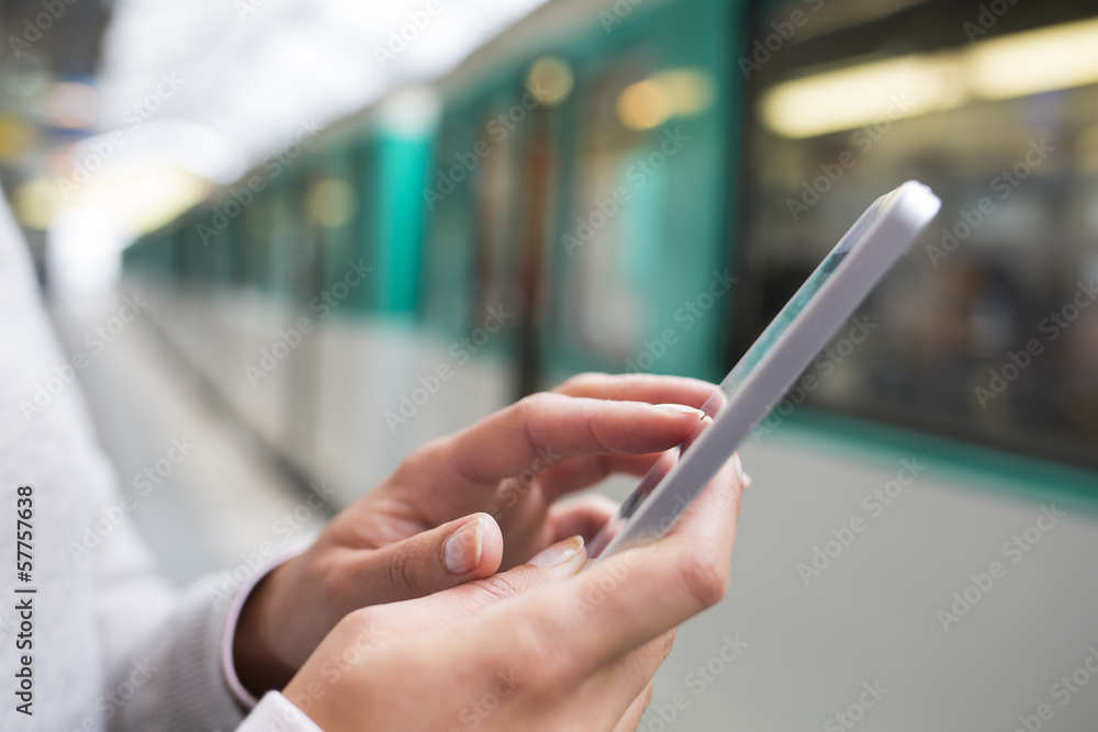 Wall mural Woman using her Mobile phone on subway platform