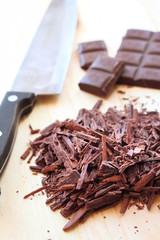 Chopped bar of dark chocolate on wooden background