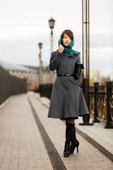 Sad young woman in grey classic coat with a handbag