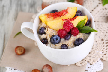 Oatmeal in cup with berries on napkins on wooden table