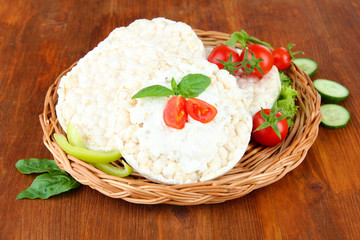 Tasty crispbreads with vegetables on wooden background