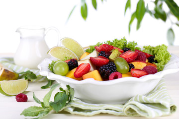 Fruit salad in plate on wooden table on bright background