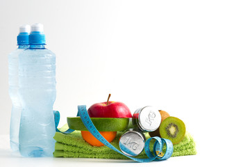 Obraz premium Hantle fitness z owocami i wodą na białym tle.