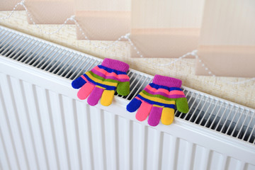 Knitted gloves drying on heating radiator