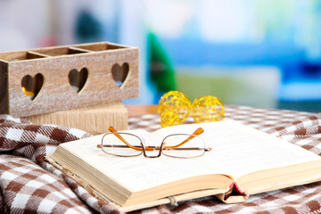 Composition with old book, eye glasses, candles, and plaid