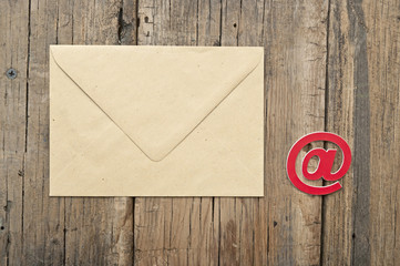 E-mail symbol and blank brown envelope on old wooden background