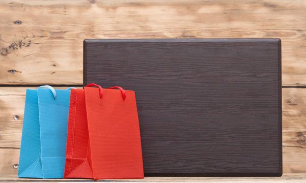 colorful shopping bags and blank wood plate with copy space for