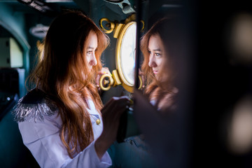 Pretty woman sailor looking through window of battleship