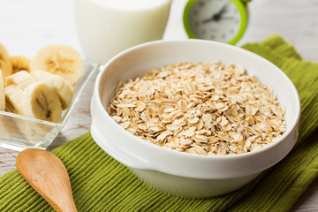 Oat flakes in bowl with banana and milk