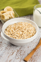 Oat flakes in bowl with banana and milk
