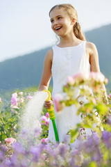 Fototapeta na wymiar Watering - beautiful girl watering roses 