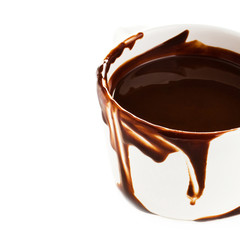 Cup of hot chocolate cocoa flow on white background, close up