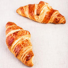Fresh Croissants on linen tablecloth on a table, closeup.