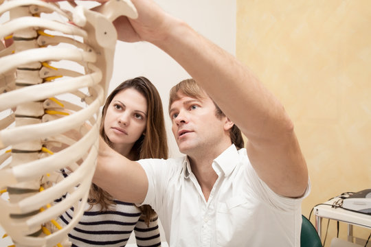 Chiropractor explains Patient using plastic model