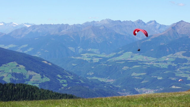 Colorful hang glider in sky over mountains, Kronplatz, Italy