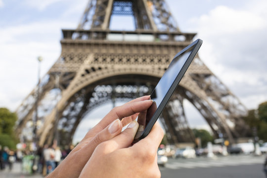 Woman Using Her Smart Phone In Front Of Eiffel Tower