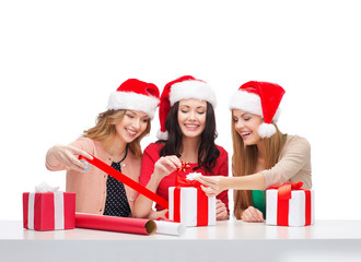 smiling women in santa helper hats with gift boxes