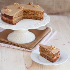 Homemade coffee and walnut cake on a stand with a cut out piece,