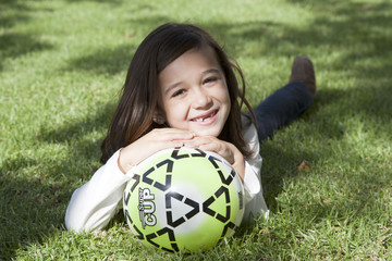 Ni&ntilde;a apoyando la sonrisa en una pelota