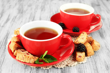 Cups of tea with cookies and blackberry on table close-up