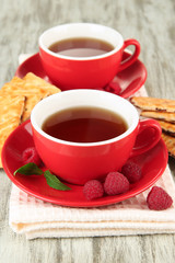 Cups of tea with cookies and raspberries on table close-up