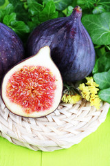 Ripe figs in leaves on wooden table close-up