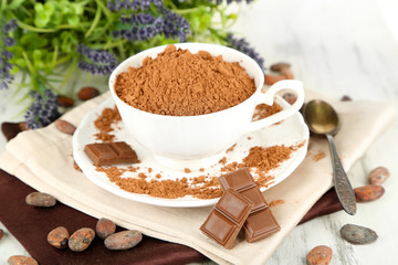 Cocoa powder in cup on napkin on wooden table