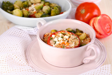 Stuffed tomatoes in pan and bowl on wooden table close-up