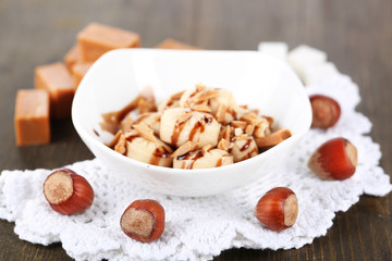 Many toffee in bowl on napkin on wooden table