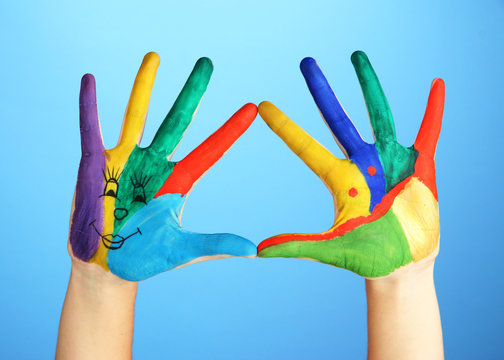 Painted hands with smile on blue background