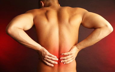 Young man with back pain on dark background