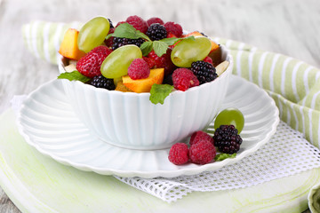 Fruit salad in bowl, on wooden background