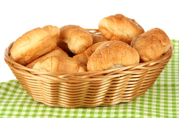 Tasty croissants in wicker basket on table on white background